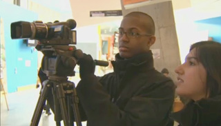 Two students working with a tripod-mounted video camera.