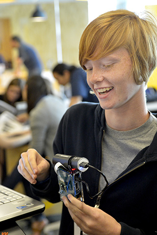 A photograph of a girl holding parts of a programmable camera as part of the Girls Who Build Cameras workshop.